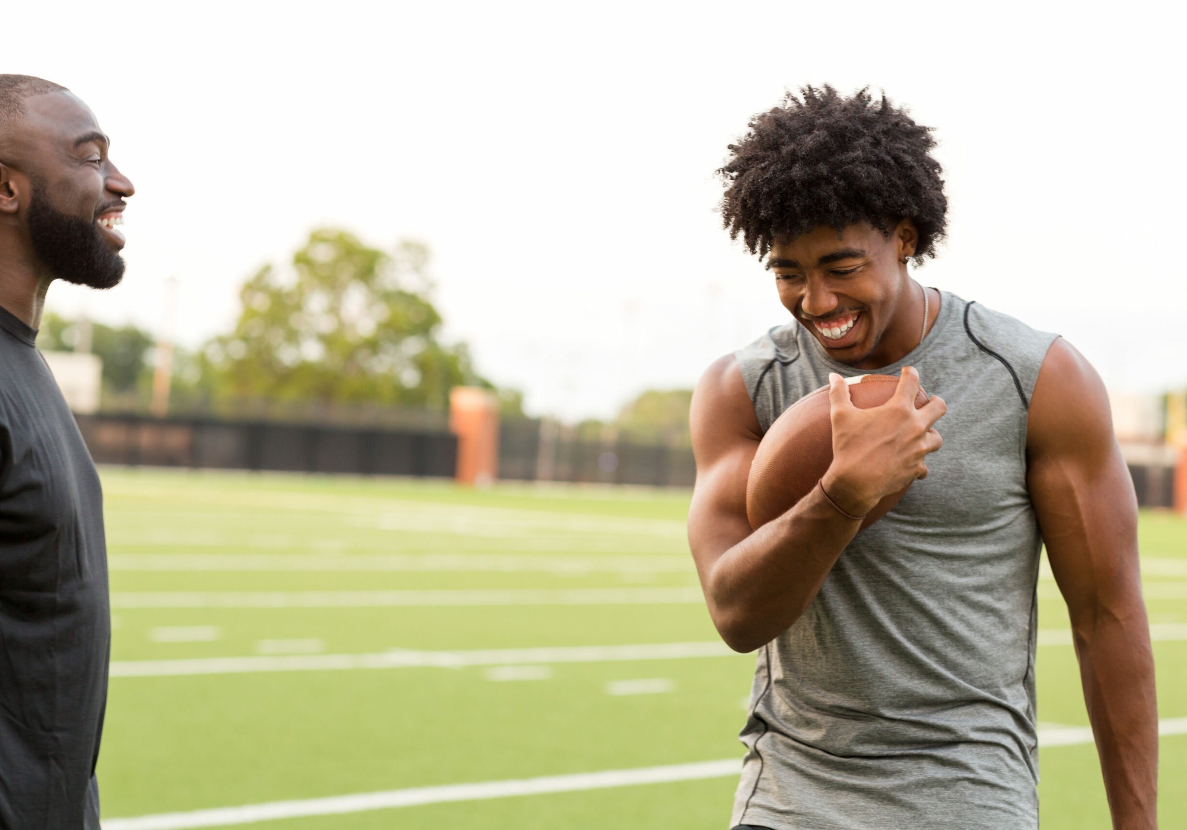 American Football coach teaching and training a young athlete.